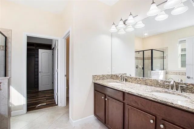 a bathroom with a granite countertop double vanity sink a vanity and a large mirror