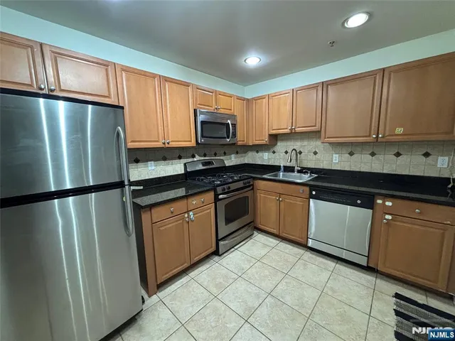 a kitchen with stainless steel appliances granite countertop a refrigerator a sink a stove a microwave and cabinets