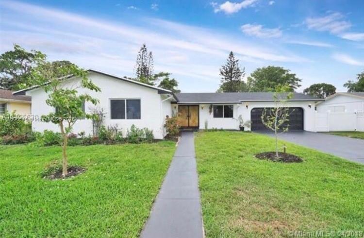 a front view of a house with a yard and potted plants