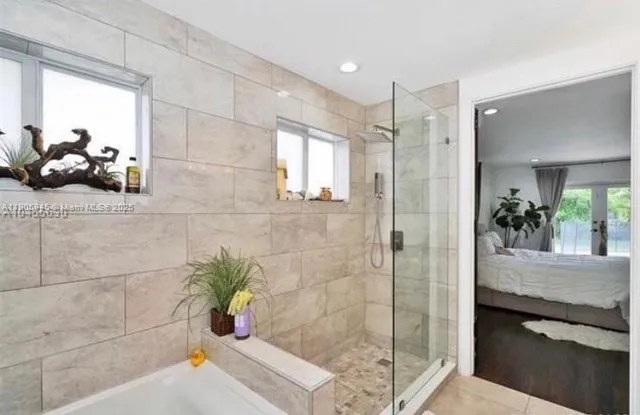 a bathroom with a tub shower and mirror