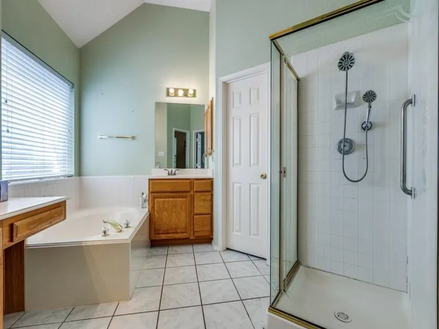a bathroom with a tub a sink a mirror and a shower