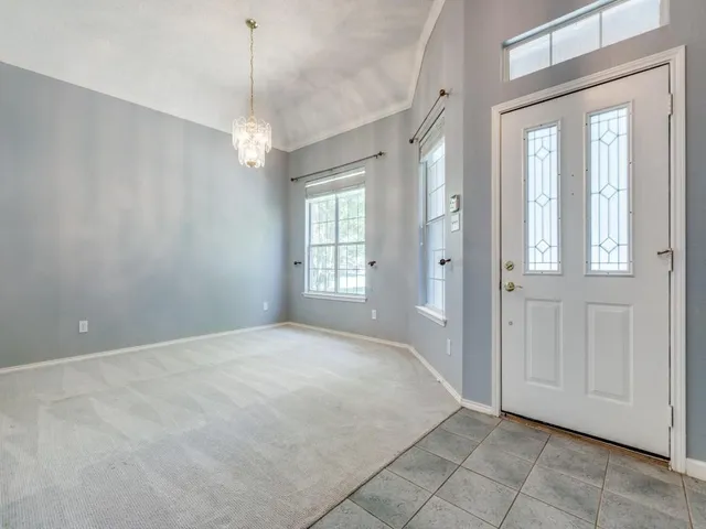 a view of an empty room with window and chandelier fan