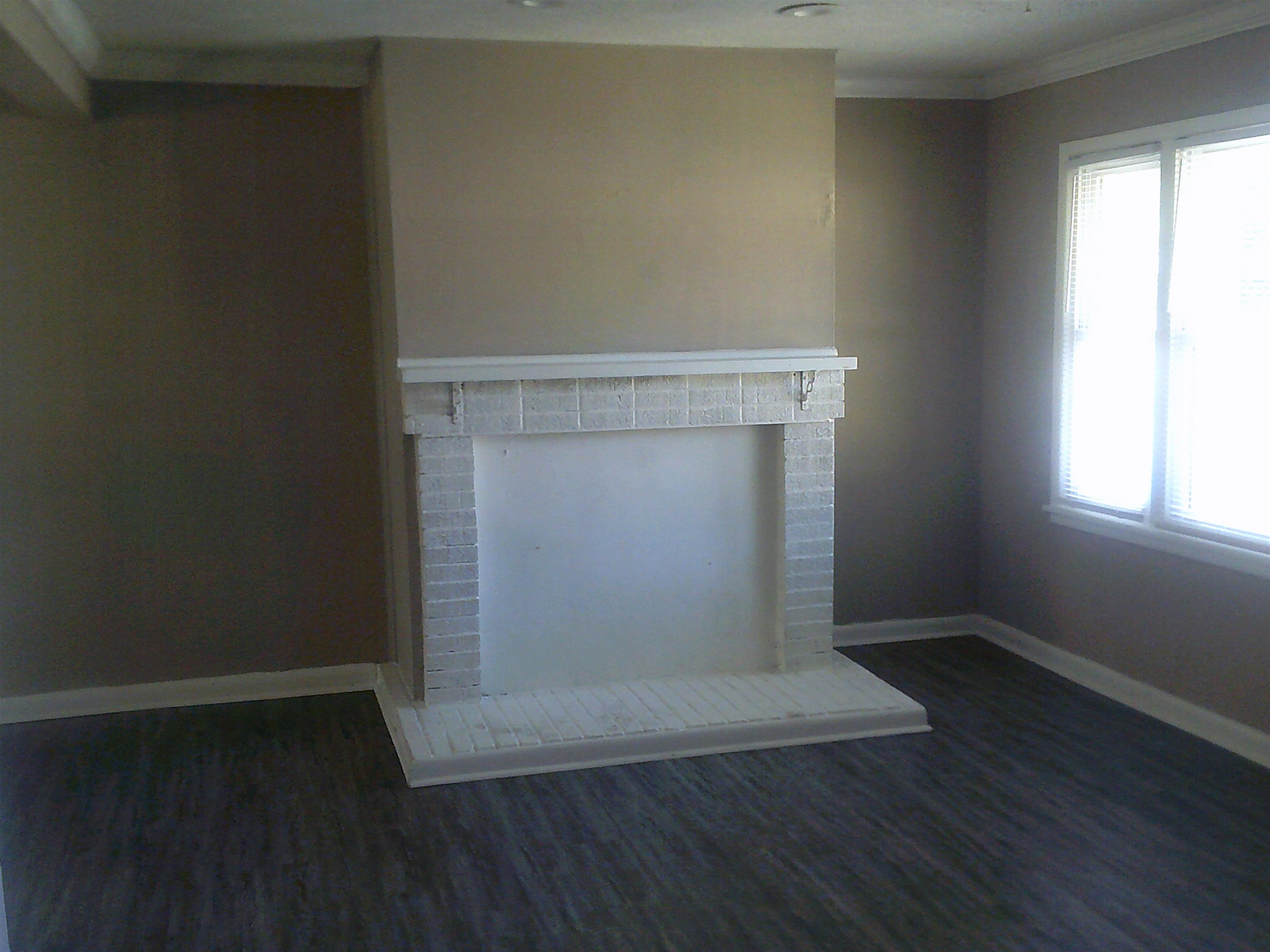 253 East Raines Road Memphis, TN 38109 - Photo 6 of 14 Unfurnished living room featuring dark wood-style flooring, ornamental molding, and a fireplace