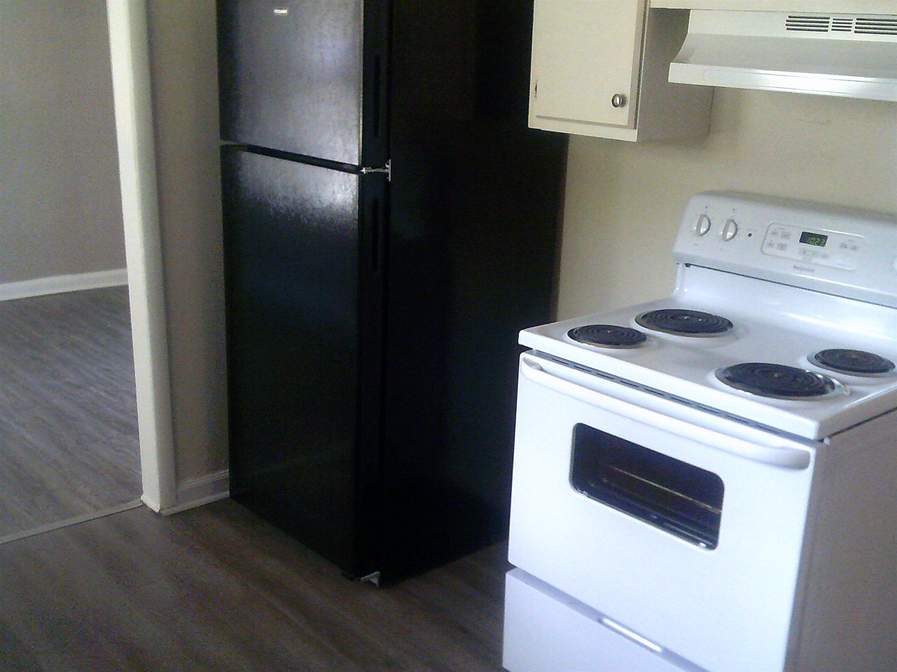 253 East Raines Road Memphis, TN 38109 - Photo 8 of 14 Kitchen with dark wood finished floors, white electric range oven, under cabinet range hood, white cabinets, and freestanding refrigerator