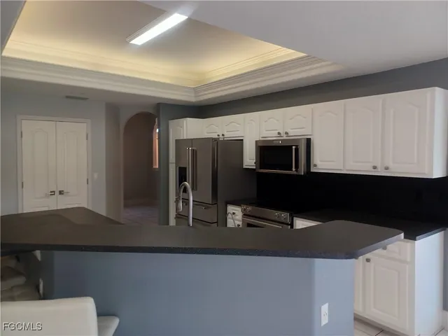 a view of an empty room with a window and a kitchen
