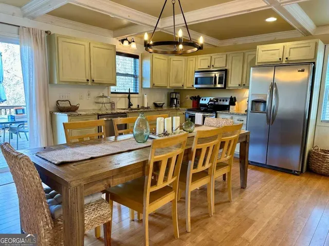 a kitchen with stainless steel appliances granite countertop a dining table chairs refrigerator and microwave