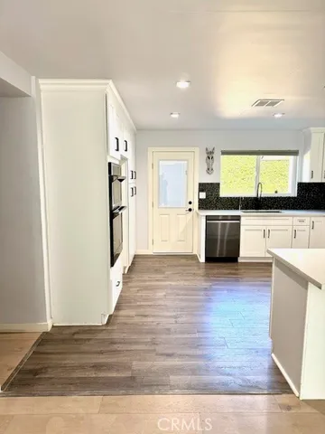a view of kitchen with stainless steel appliances granite countertop cabinets and wooden floor