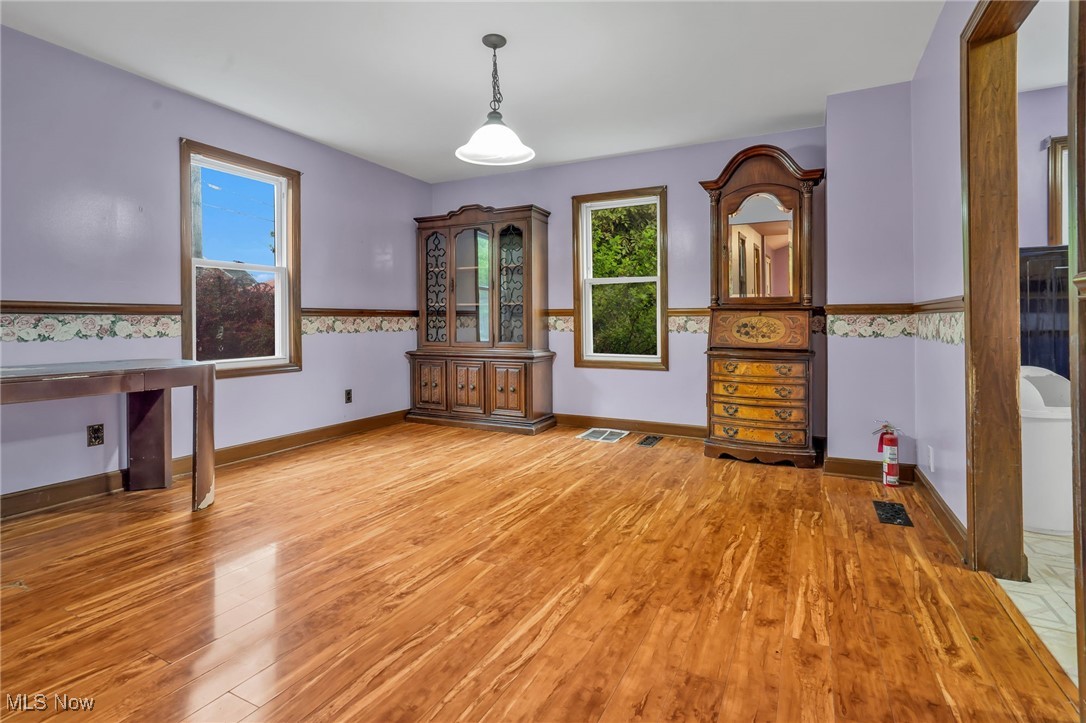 Unfurnished dining area featuring light wood-type flooring and baseboards