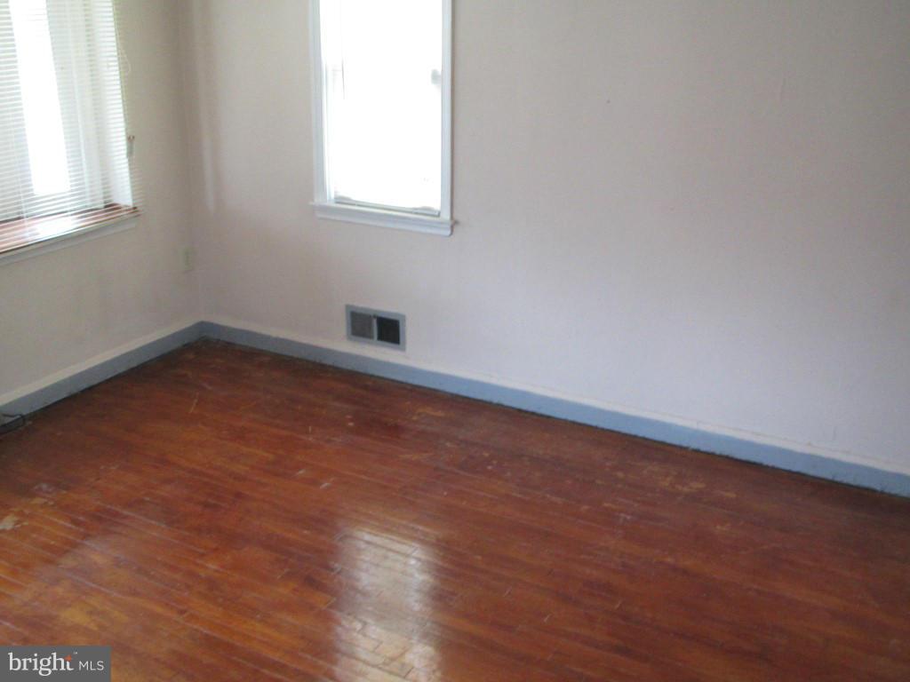 1936 Penhall Road Baltimore, MD 21222 - Photo 4 of 14 an empty room with wooden floor and windows