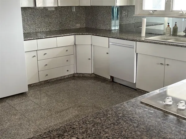 a kitchen with granite countertop white cabinets and a stove