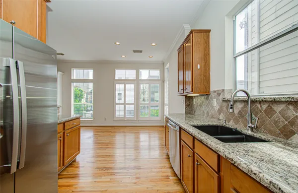 a kitchen with stainless steel appliances granite countertop a sink a stove and a wooden floors