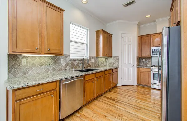 a kitchen with stainless steel appliances granite countertop wooden cabinets a sink and dishwasher with wooden floor