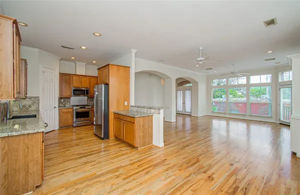 a large kitchen with cabinets wooden floor and stainless steel appliances