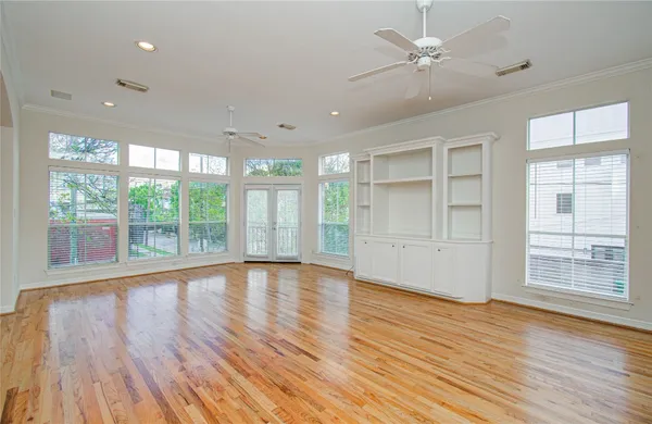 a view of an empty room with a window and wooden floor