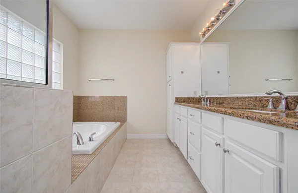 a bathroom with a granite countertop sink and white tub