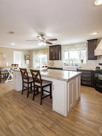 a kitchen with stainless steel appliances granite countertop a table chairs sink and cabinets