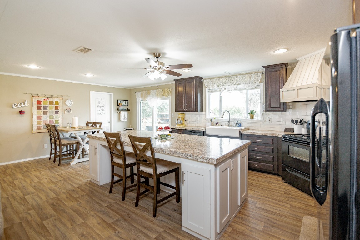 1891 Dworaczyk Road Yorktown, TX 78164 - Photo 35 of 48 a kitchen with stainless steel appliances kitchen island granite countertop a table chairs a sink and dishwasher a refrigerator with wooden floor