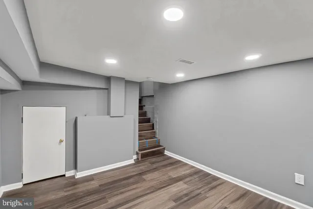a view of an empty room with wooden floor and closet