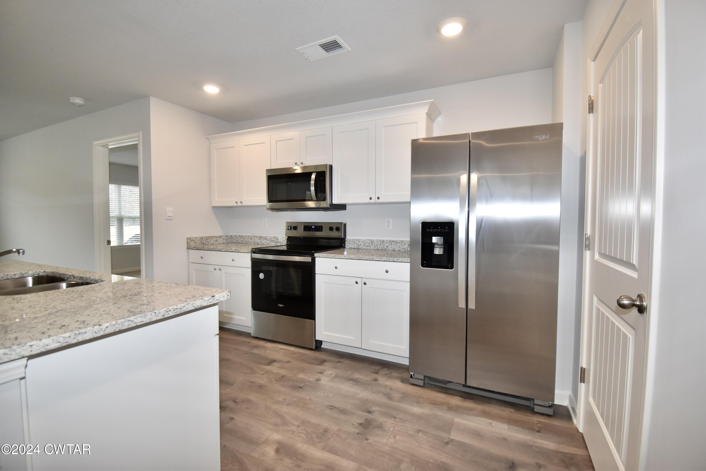 48 Vintage Grove Road Jackson, TN 38305 - Photo 4 of 19 a kitchen with stainless steel appliances granite countertop a refrigerator a stove a sink and a microwave