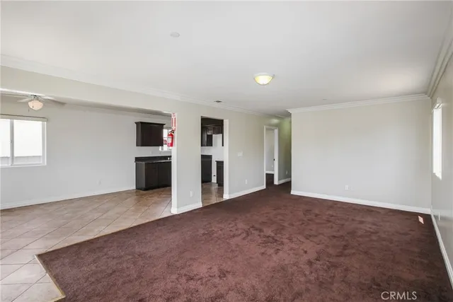 an empty room with kitchen view and a fireplace
