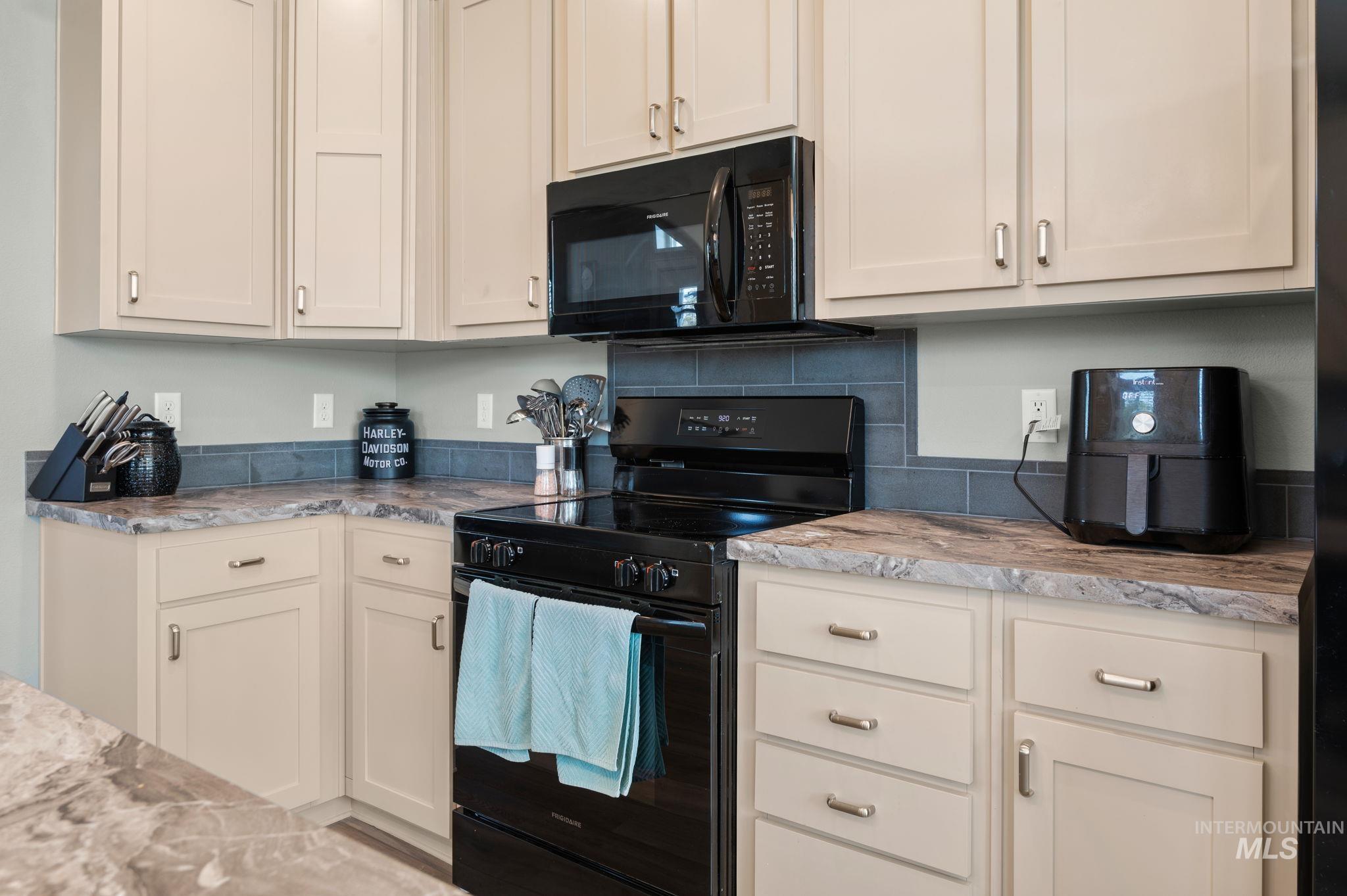 837 Burrell Avenue Lewiston, ID 83501 - Photo 26 of 32 Kitchen with black appliances, light stone countertops, and white cabinetry