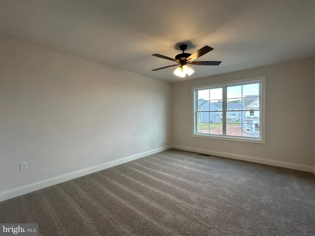 an empty room with a window and a fan