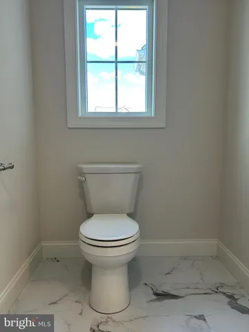 a white toilet sitting in a bathroom next to a window