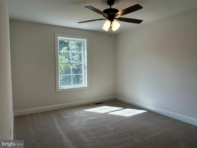 an empty room with a window and a fan