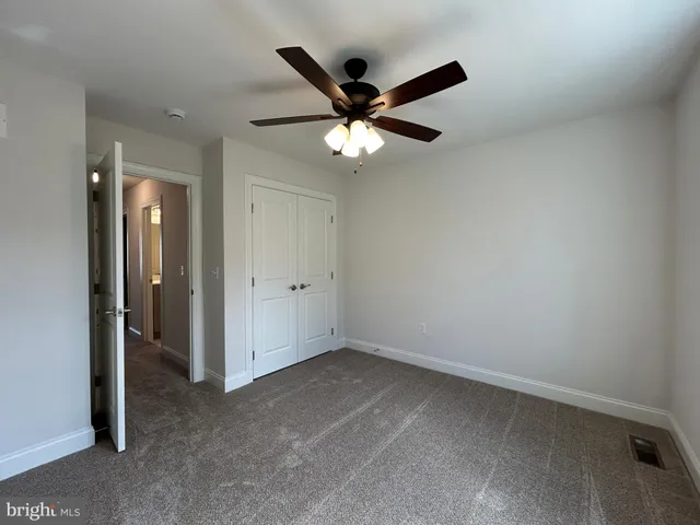 an empty room with closet and a ceiling fan