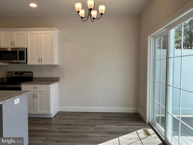 a kitchen with granite countertop a stove a microwave and white cabinets