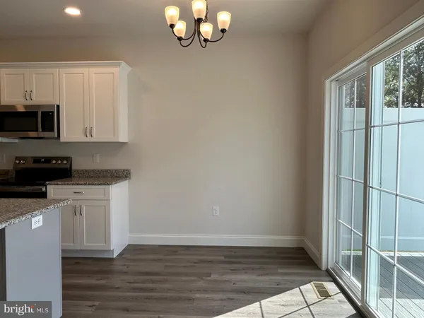 a kitchen with granite countertop a stove a microwave and white cabinets