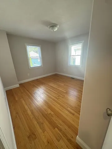 a view of empty room with window and wooden floor