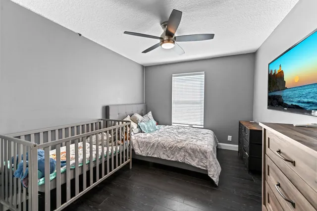 a bedroom with a bed and a flat tv screen on the dresser