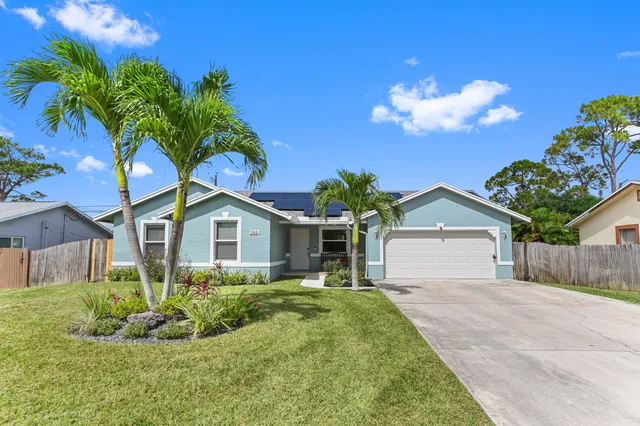a front view of a house with a yard and potted plants