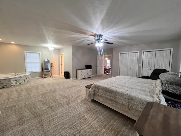 a spacious bedroom with a bed a chandelier and dresser