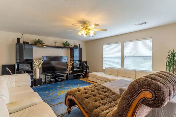 a living room with furniture a ceiling fan and a flat screen tv