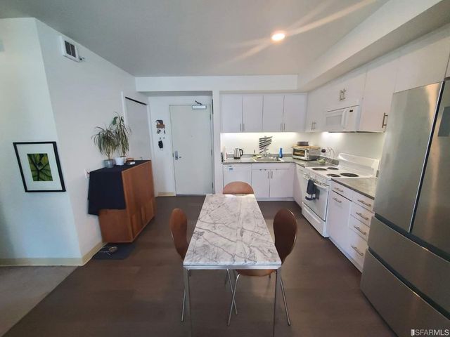 a kitchen with stainless steel appliances granite countertop a refrigerator oven a sink dishwasher and white cabinets next to a window