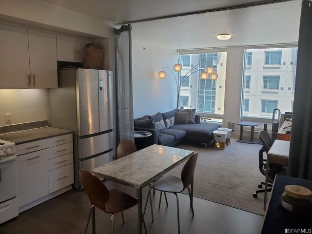 a living room with furniture a large window and stainless steel appliances