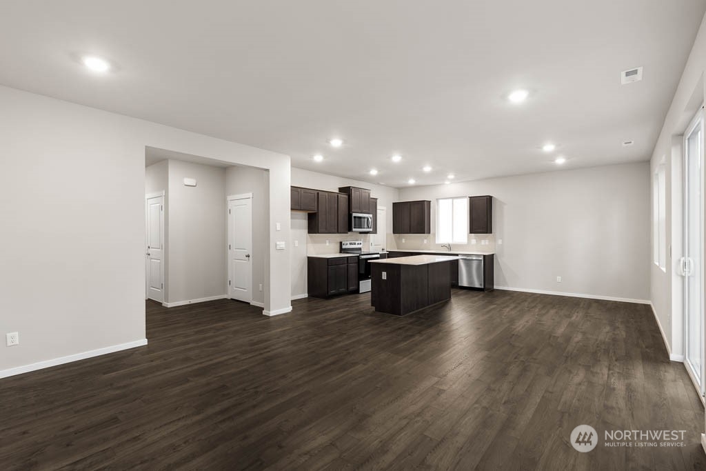 18937 Liberty Rdg Lane, Unit 955 Puyallup, WA 98374 - Photo 4 of 19 a large white kitchen with kitchen island a sink wooden floor and a refrigerator