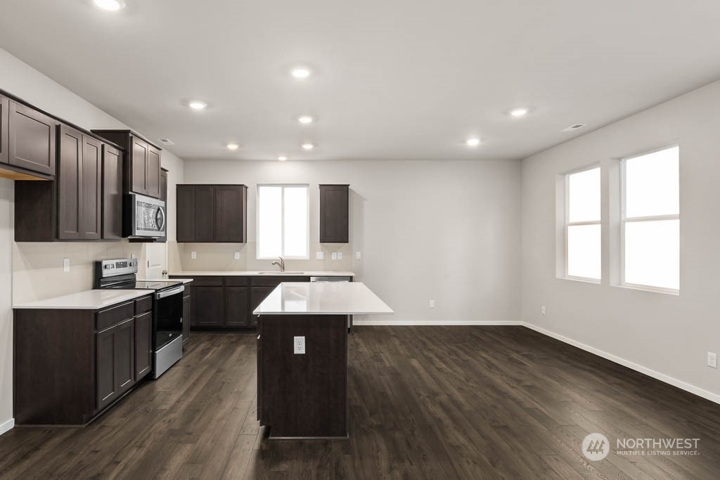 18937 Liberty Rdg Lane, Unit 955 Puyallup, WA 98374 - Photo 7 of 19 a large kitchen with stainless steel appliances granite countertop a sink dishwasher a stove and a refrigerator with wooden floor