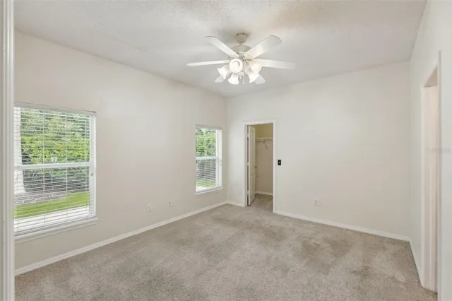 an empty room with windows and fan
