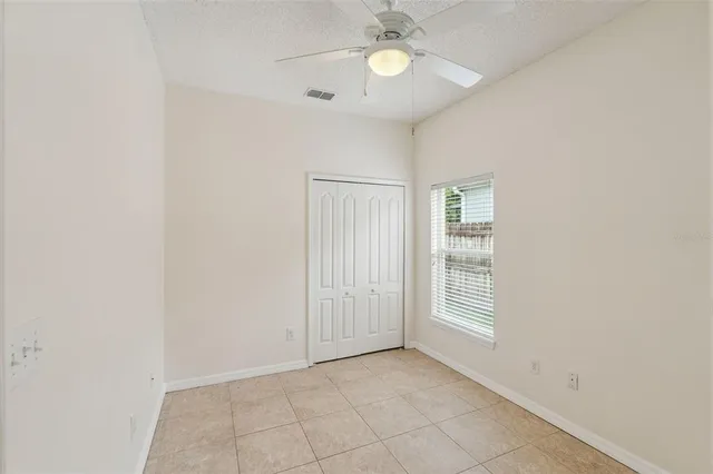 an empty room with windows and fan