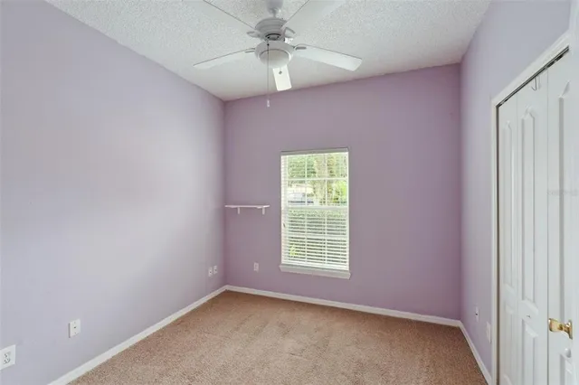 an empty room with a window and a fan