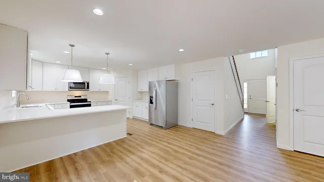 a kitchen with stainless steel appliances granite countertop a stove top oven a sink dishwasher and a refrigerator with wooden floor