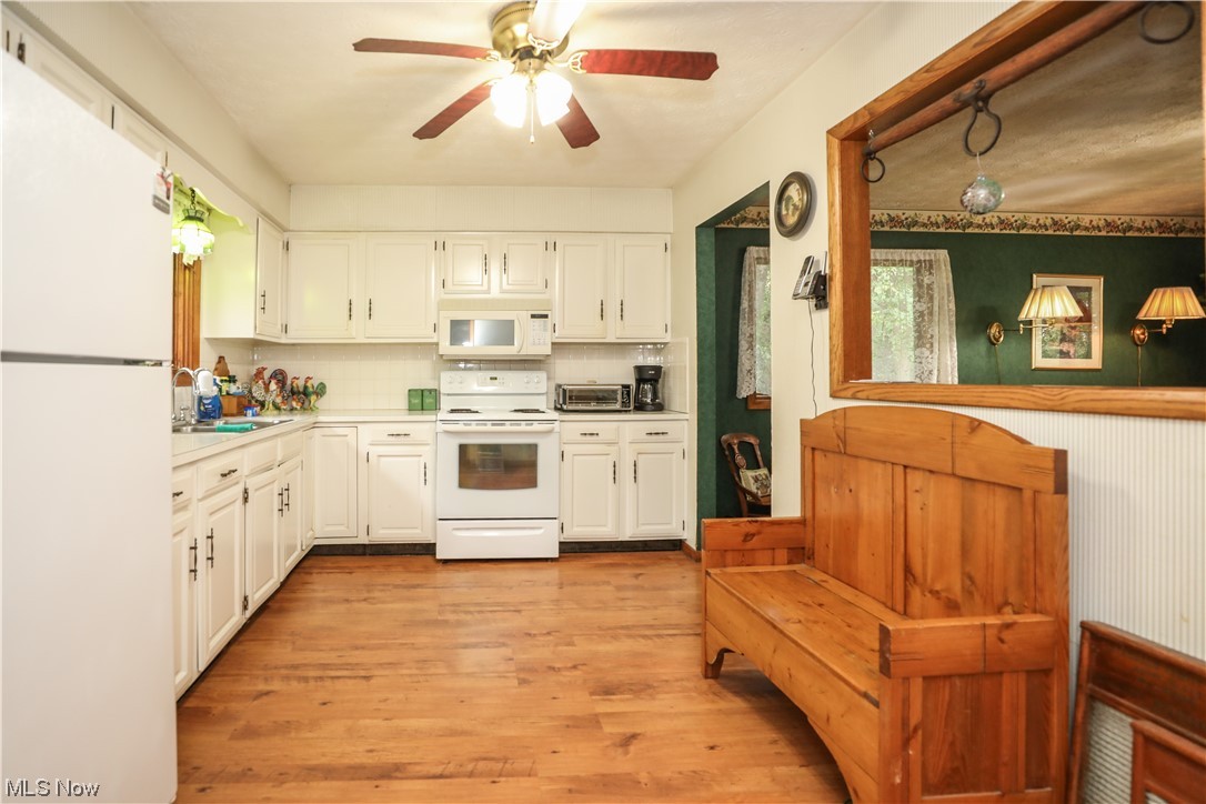 5344 Camp Road Ravenna, OH 44266 - Photo 8 of 30 Kitchen with white cabinets, light countertops, white appliances, backsplash, light hardwood floors, and ceiling fan