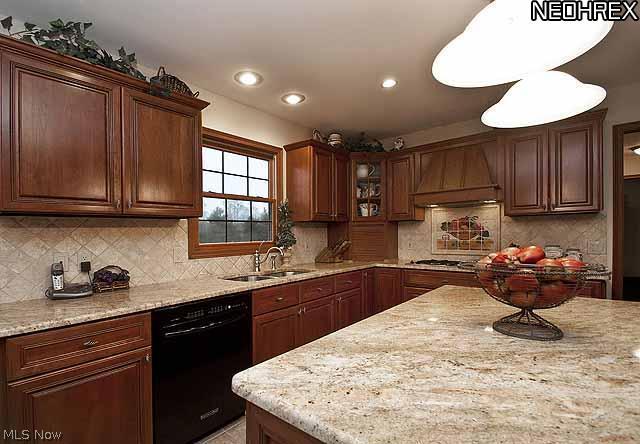 357 Longspur Road Highland Heights, OH 44143 - Photo 4 of 22 Cookâ??s dream kitchen featuring custom honey-stained cherry wood cabinets with maple interiors, gorgeous granite countertops, travertine tile backsplash, stainless steel Jenn-Air gas cooktop, large electronic double ovens, LG microwave, Kitchen Aid dishwasher, large stainless steel Kohler extra deep double sink with sprayer, appliance garage, glass front cabinet, cabinets/double pantry with pullout shelves, and a large island with eating space, walk-in bay with French door slider in breakfast room