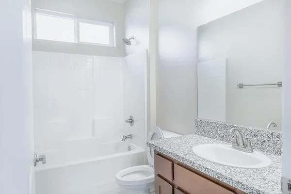 a bathroom with a granite countertop sink a toilet and shower