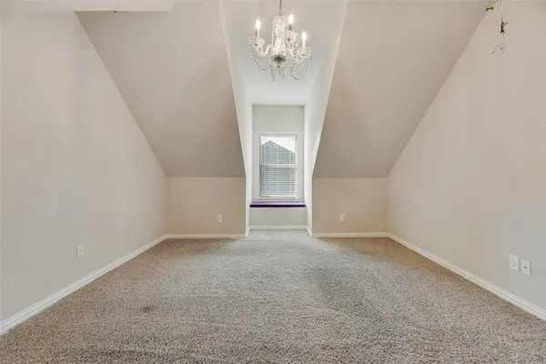 an empty room with a chandelier fan and windows