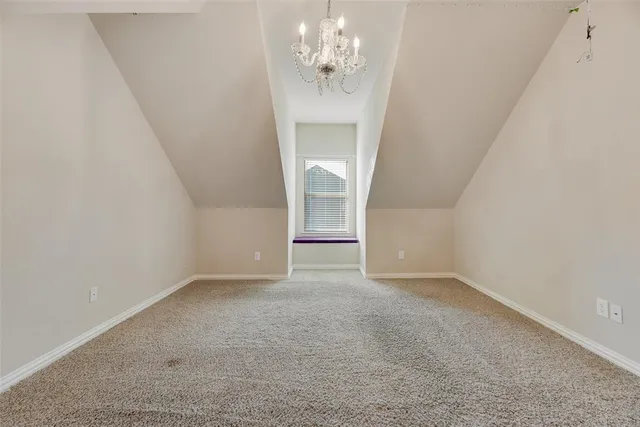 an empty room with a chandelier fan and windows