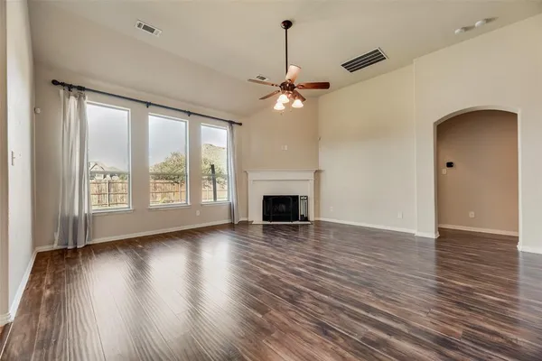a view of a livingroom with wooden floor a ceiling fan and windows